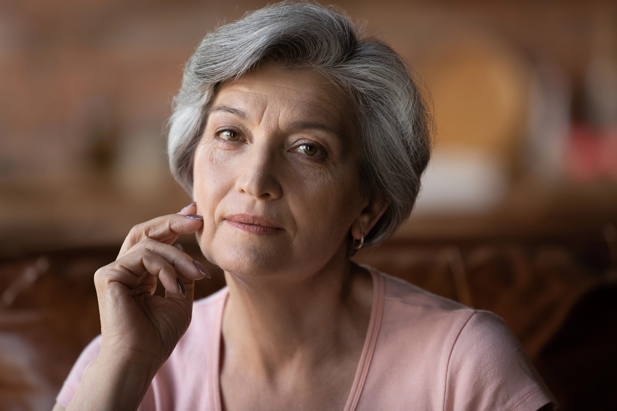 Middle Aged Women in pink shirt looking pensive into the camera.